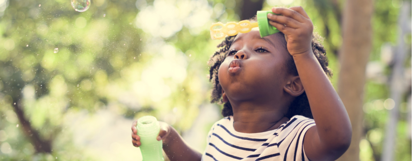 little girl blowing bubbles outside