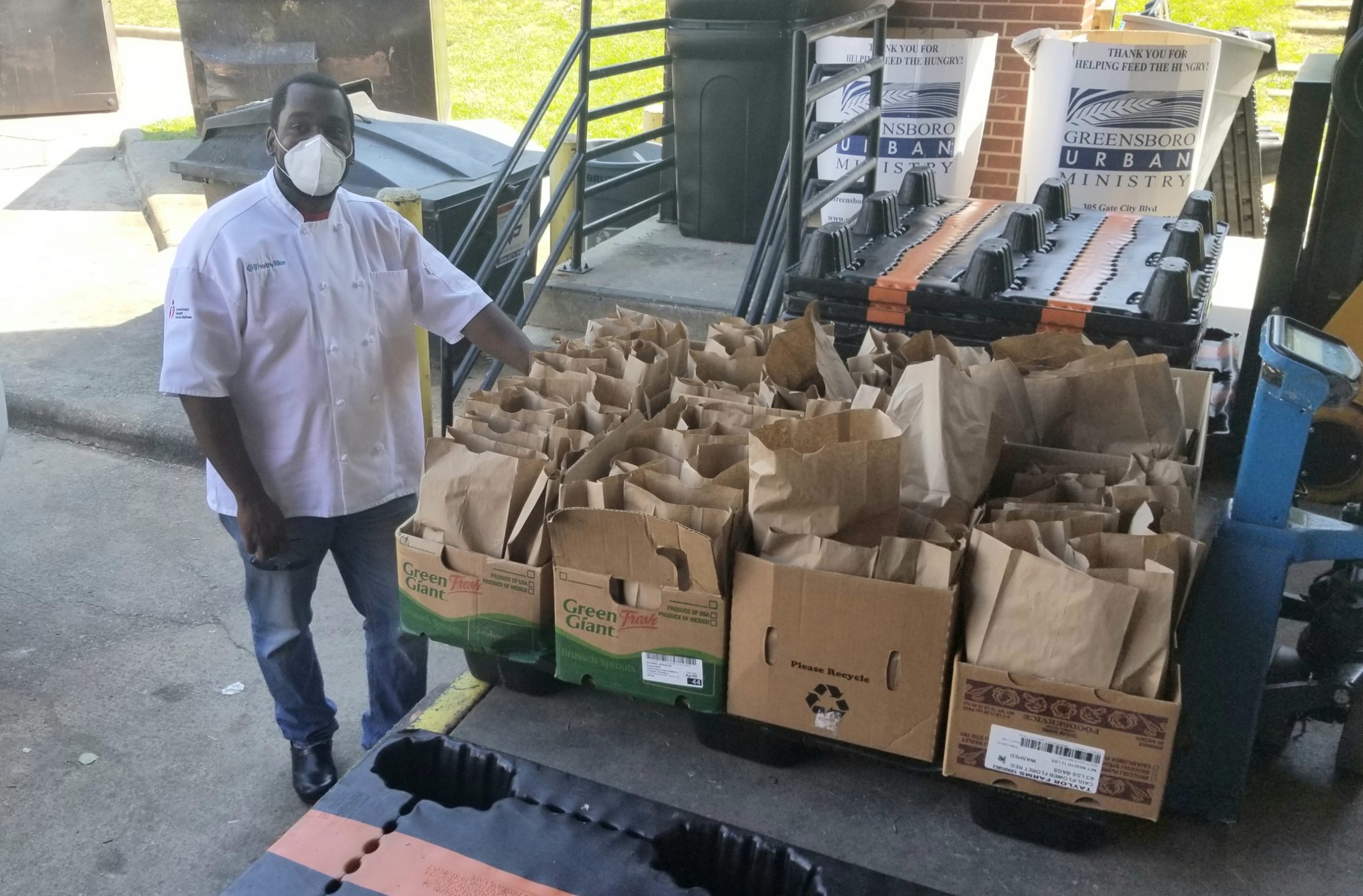 N'Gai stands next to a dozen brown bags full of meals