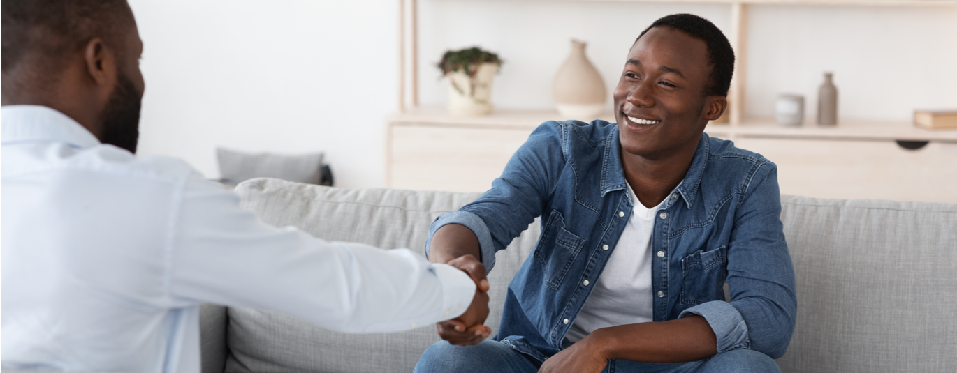 African American man and therapist shake hands, smiling